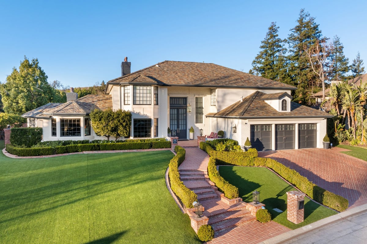 Luxury estate with manicured lawn and brick driveway
